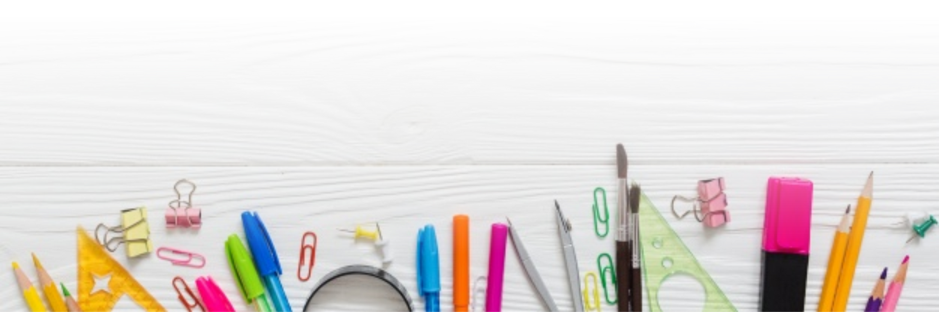 Útiles escolares de colores sobre una mesa de madera blanca